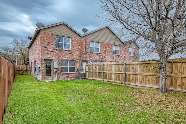 back of property with central AC and a lawn