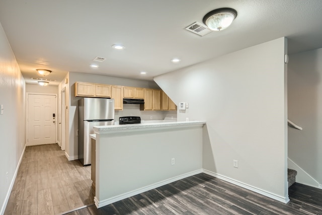 kitchen featuring black range oven, stainless steel fridge, kitchen peninsula, and light brown cabinets