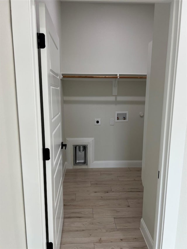 clothes washing area with electric dryer hookup, hookup for a gas dryer, hookup for a washing machine, and light hardwood / wood-style floors