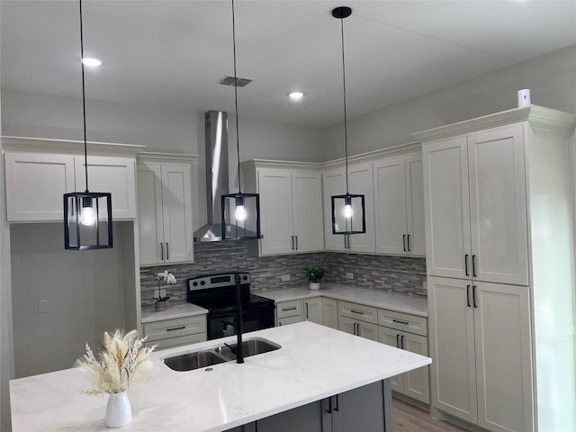 kitchen with stainless steel electric range, hanging light fixtures, and wall chimney range hood