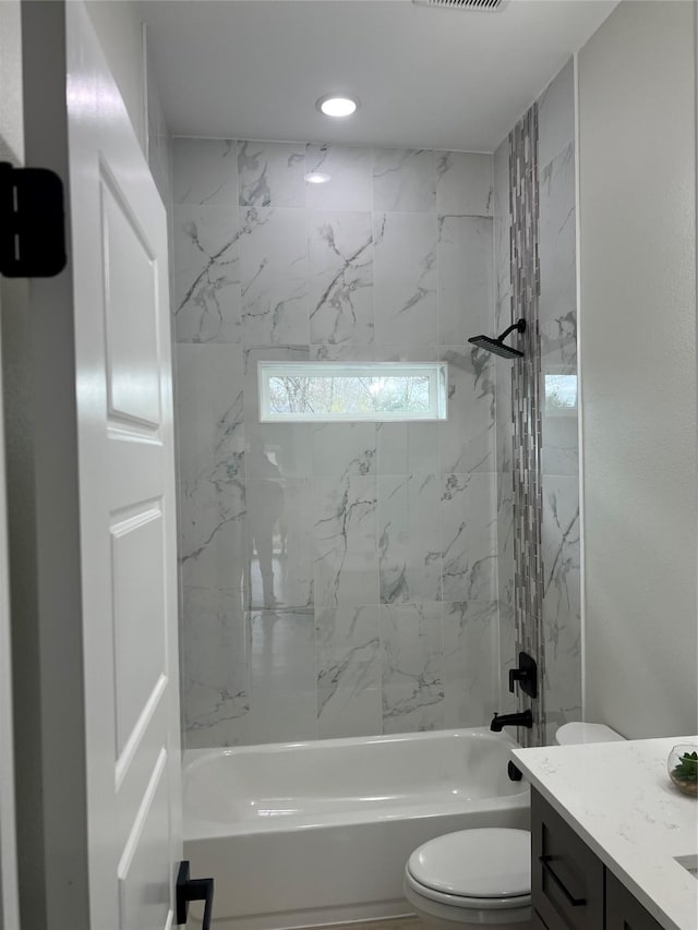 full bathroom with vanity, tiled shower / bath combo, and toilet