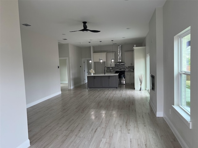 unfurnished living room featuring hardwood / wood-style flooring, ceiling fan, and a wealth of natural light