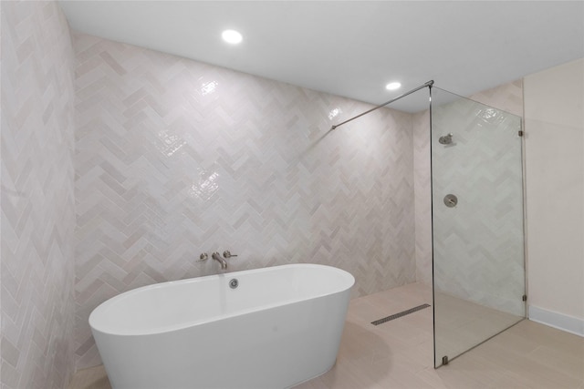 bathroom featuring tile patterned floors, tile walls, and independent shower and bath