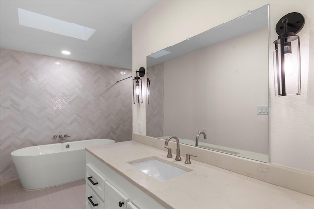 bathroom with tile patterned flooring, vanity, a washtub, and a skylight