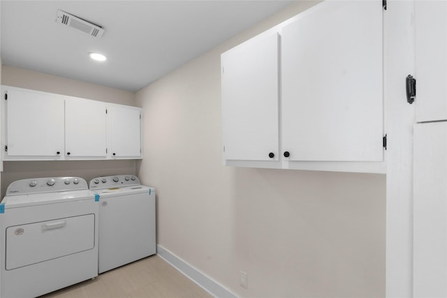 clothes washing area with washing machine and clothes dryer and cabinets