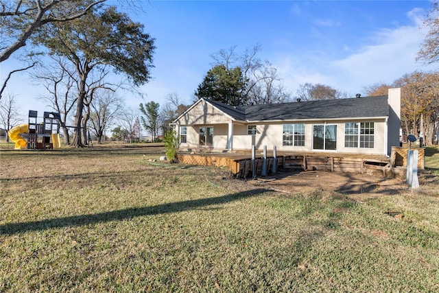 rear view of property with a playground and a lawn