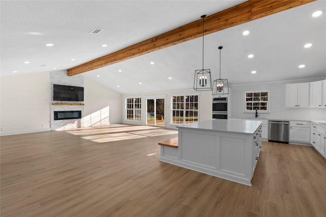 kitchen featuring appliances with stainless steel finishes, a fireplace, white cabinets, light hardwood / wood-style floors, and a kitchen island