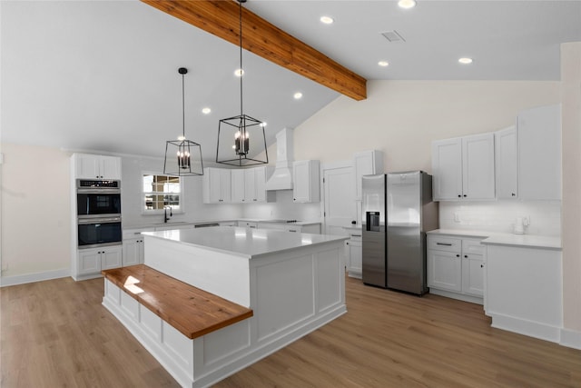 kitchen featuring appliances with stainless steel finishes, tasteful backsplash, beamed ceiling, a kitchen island, and white cabinetry