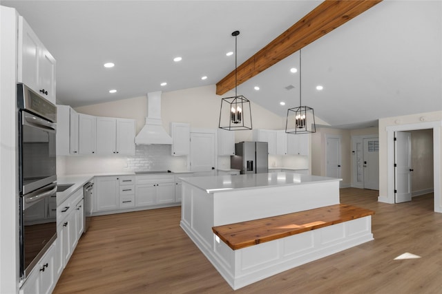 kitchen with white cabinetry, a center island, decorative backsplash, appliances with stainless steel finishes, and custom exhaust hood