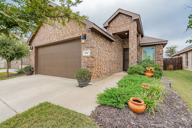 view of front of house featuring an attached garage, driveway, and brick siding