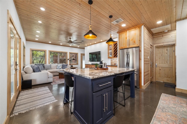 kitchen with pendant lighting, stainless steel fridge, a breakfast bar area, and wooden walls