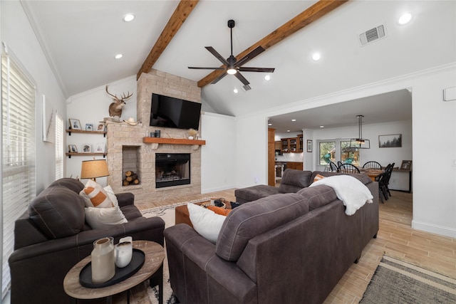 living room featuring vaulted ceiling with beams, ceiling fan, a stone fireplace, and crown molding