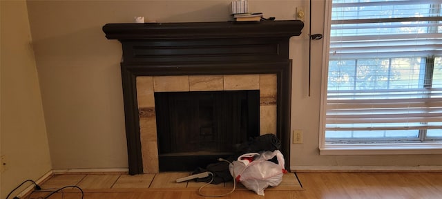 details with wood-type flooring and a tiled fireplace