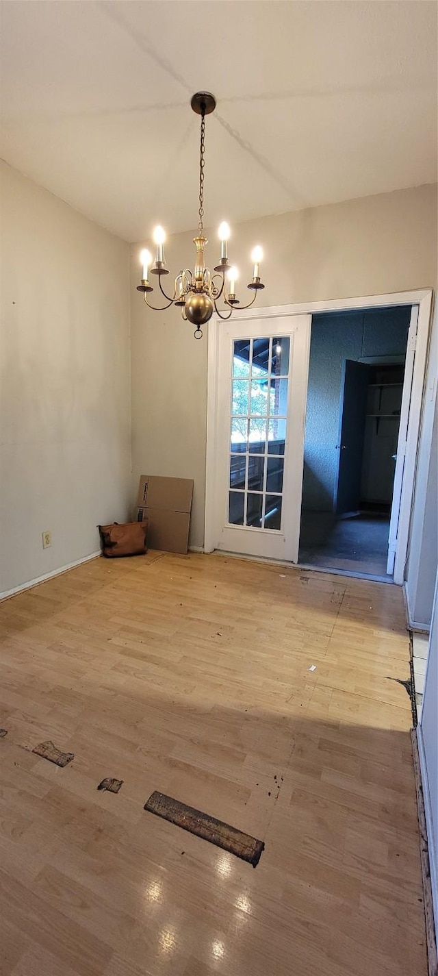 unfurnished dining area with hardwood / wood-style floors and a notable chandelier