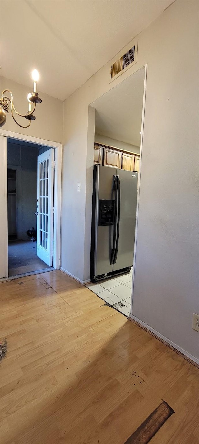 kitchen with a chandelier, stainless steel refrigerator with ice dispenser, and light wood-type flooring