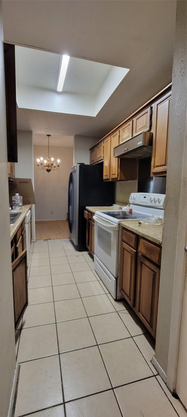 kitchen with white appliances, exhaust hood, decorative light fixtures, a notable chandelier, and light tile patterned flooring