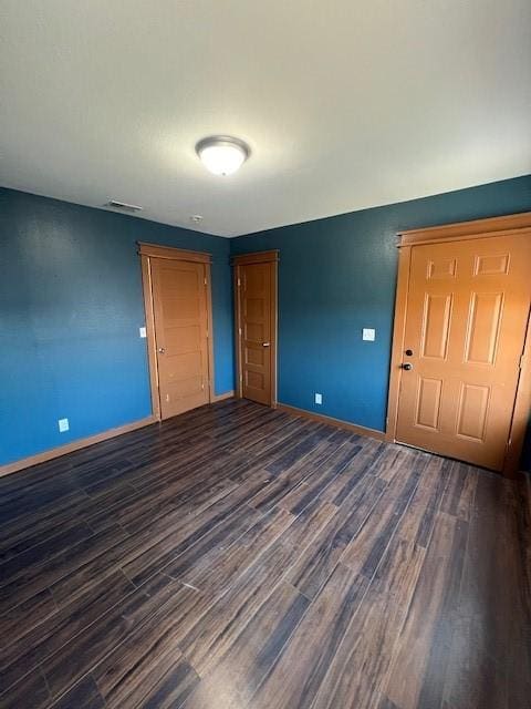 unfurnished room with visible vents, baseboards, and dark wood-type flooring