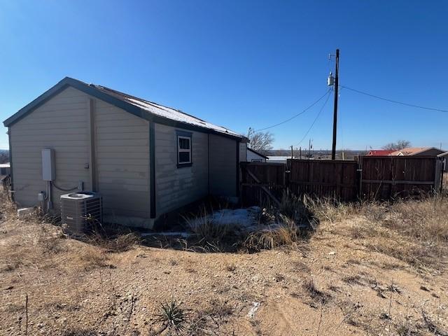 view of side of home featuring central air condition unit and fence