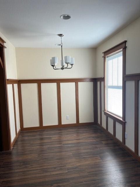 unfurnished dining area featuring an inviting chandelier and dark wood-type flooring