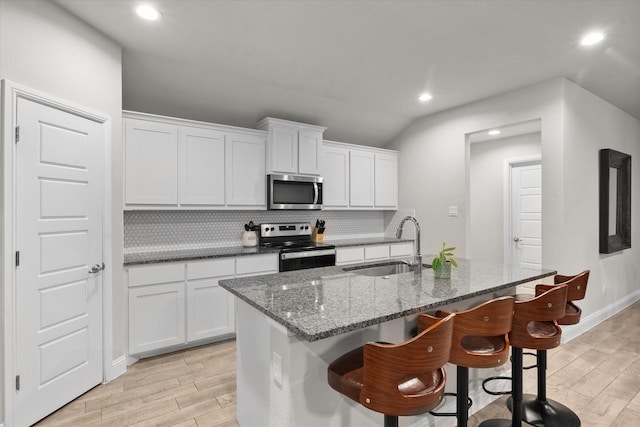 kitchen with a kitchen island with sink, white cabinets, sink, appliances with stainless steel finishes, and tasteful backsplash