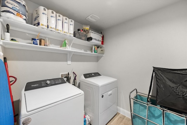 laundry room featuring washing machine and clothes dryer and light hardwood / wood-style flooring