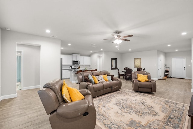 living room with ceiling fan and light hardwood / wood-style flooring