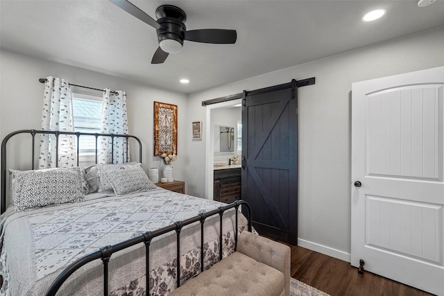 bedroom with ceiling fan, a barn door, dark hardwood / wood-style floors, and connected bathroom