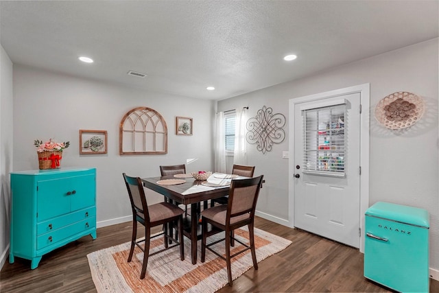 dining area with a textured ceiling and dark wood-type flooring