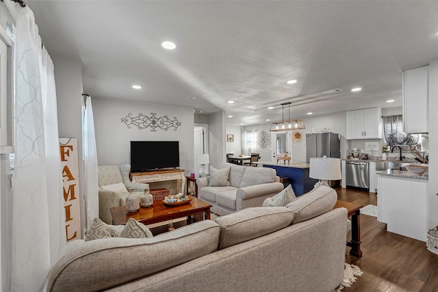 living room featuring a textured ceiling, dark wood-type flooring, and a healthy amount of sunlight