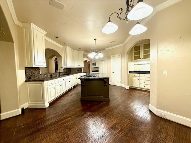 kitchen with white cabinets, a center island, backsplash, and decorative light fixtures