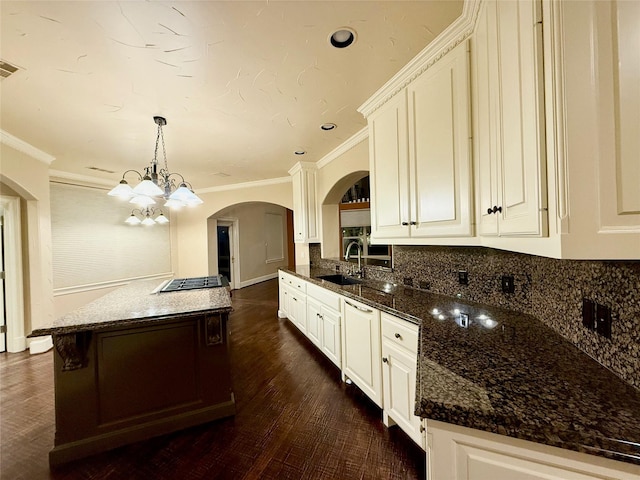 kitchen with decorative light fixtures, a notable chandelier, dark stone countertops, sink, and ornamental molding