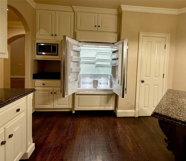 interior space featuring stainless steel microwave, dark stone counters, dark hardwood / wood-style flooring, and crown molding