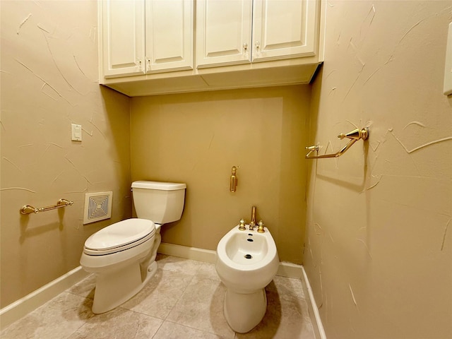 bathroom featuring toilet, a bidet, and tile patterned floors