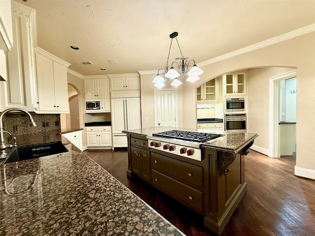 kitchen with white cabinetry, sink, dark stone countertops, and built in appliances