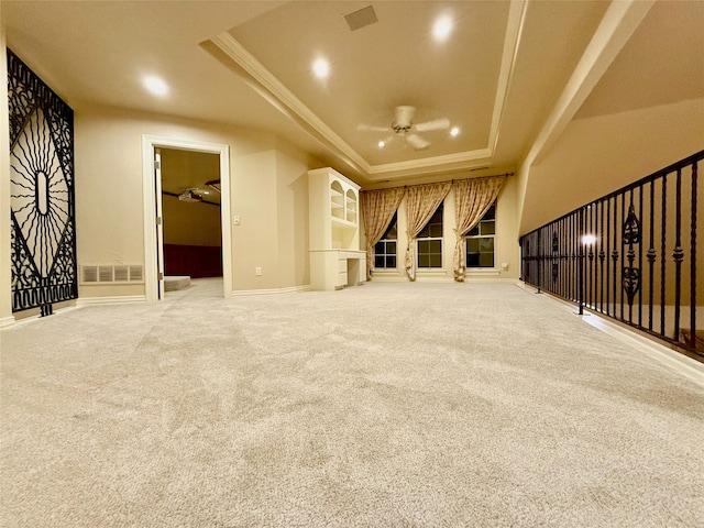 unfurnished living room with ceiling fan, a tray ceiling, and carpet flooring