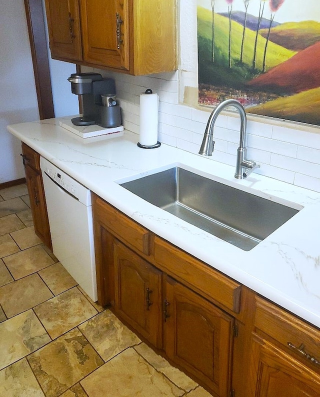 kitchen with sink, white dishwasher, and tasteful backsplash