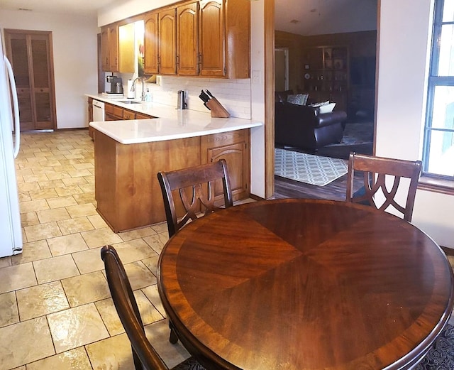 kitchen featuring kitchen peninsula, sink, tasteful backsplash, and white appliances