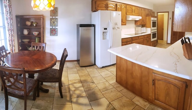 kitchen featuring backsplash, white appliances, kitchen peninsula, and hanging light fixtures