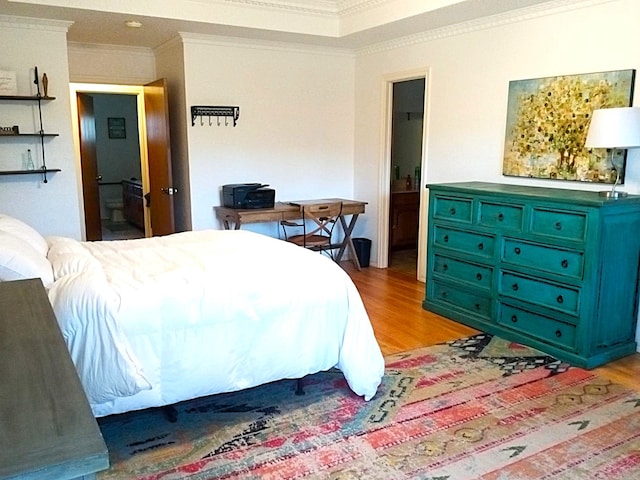 bedroom with light wood-type flooring, connected bathroom, and ornamental molding