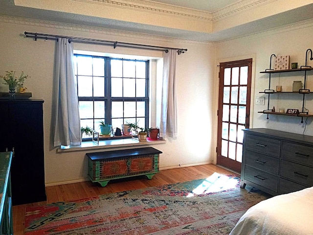 bedroom with a tray ceiling, light hardwood / wood-style flooring, and crown molding