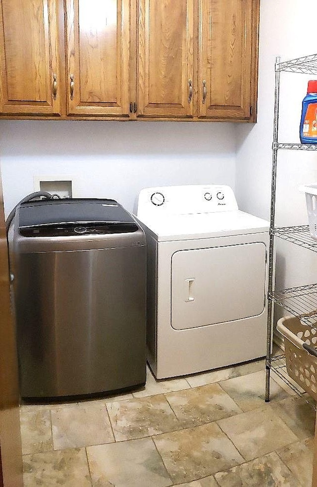 clothes washing area with cabinets and washing machine and clothes dryer