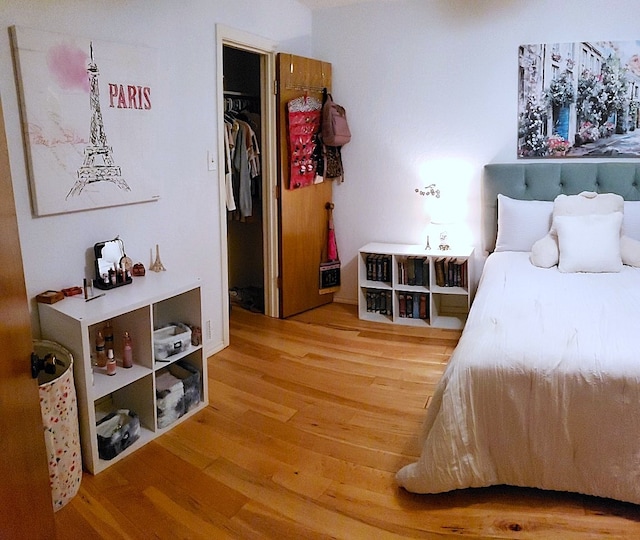 bedroom with a closet, a spacious closet, and hardwood / wood-style floors