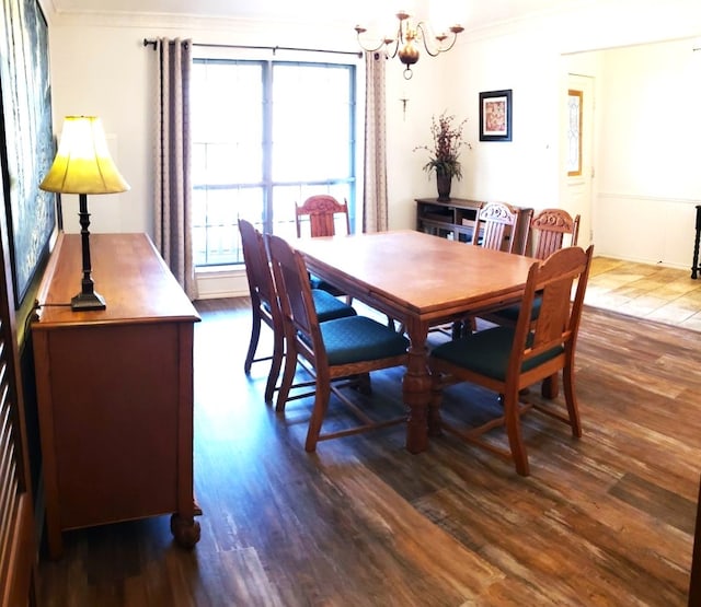 dining space with ornamental molding, dark wood-type flooring, and an inviting chandelier