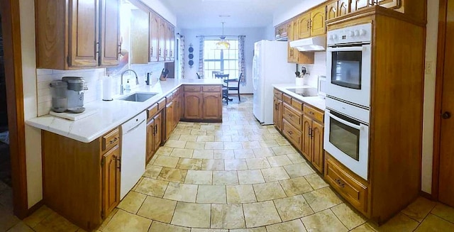 kitchen featuring decorative light fixtures, sink, white appliances, and backsplash