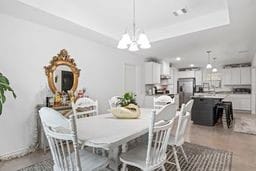 dining area with a tray ceiling and an inviting chandelier