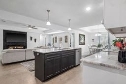 kitchen featuring dishwasher, pendant lighting, a kitchen island with sink, and sink