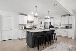 kitchen featuring white cabinetry, a center island with sink, and appliances with stainless steel finishes