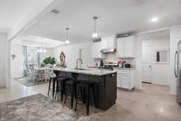 kitchen featuring a center island with sink, white cabinets, and hanging light fixtures