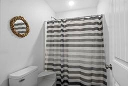 bathroom with a shower with shower curtain and toilet