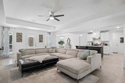 living room with a raised ceiling and ceiling fan